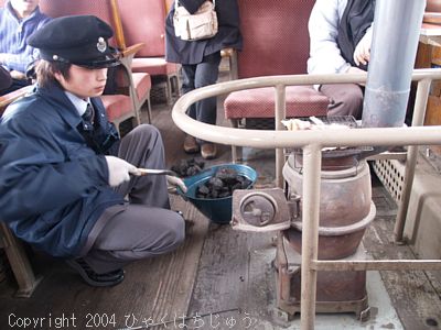 石炭をストーブに入れる車掌さん(網の上には、スルメが焼けてます)